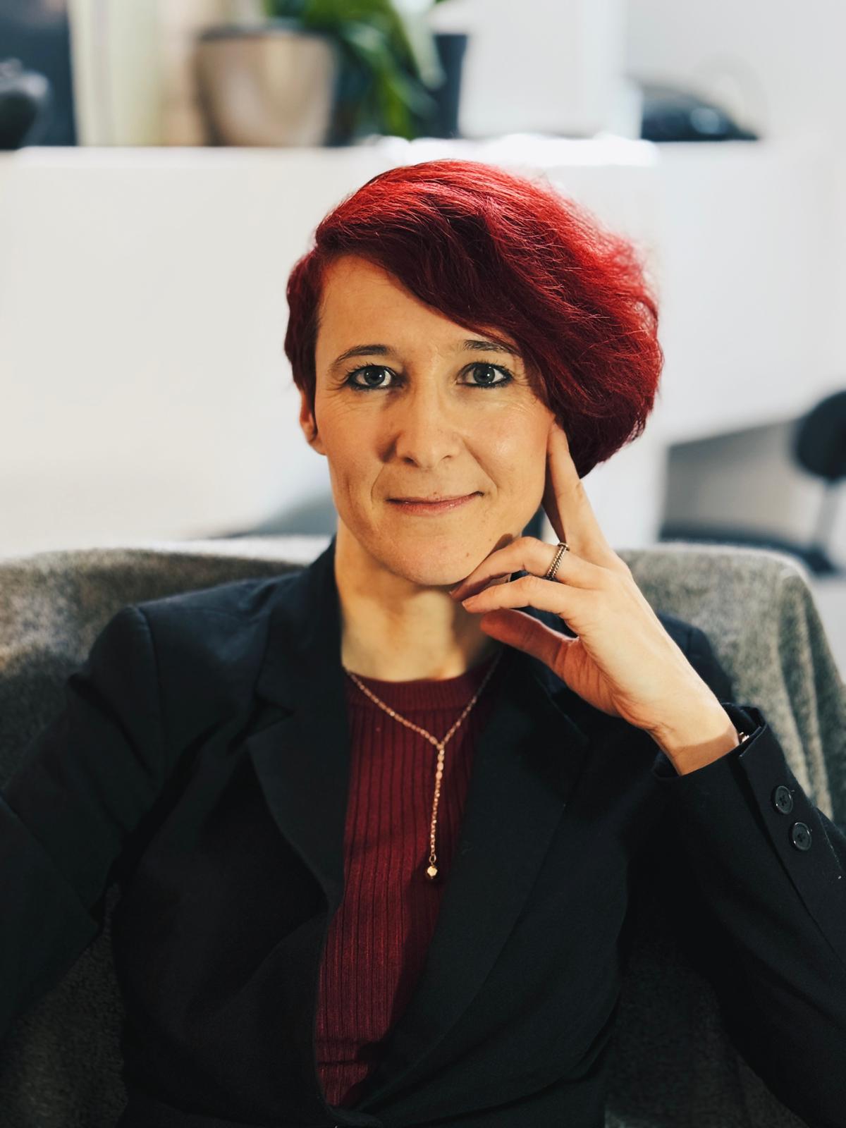 Urša Young, psychologist and coach, in a red top and black blazer